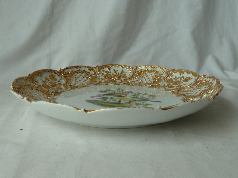 A circular white Meissen porcelain dish featuring a hand-painted illustration of two birds on branches, surrounded by a heavily gilded and pierced Rococo rim. View VI