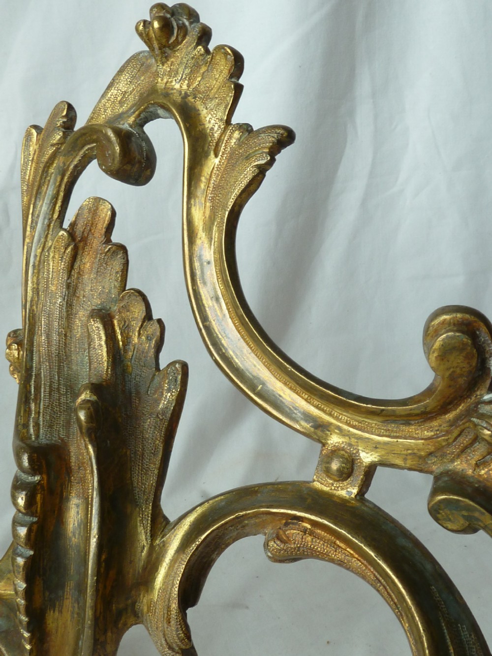 A pair of cast gilt brass French Rococo style fire dogs with elaborate acanthus leaf C-scroll design on small pedestal feet. View IV