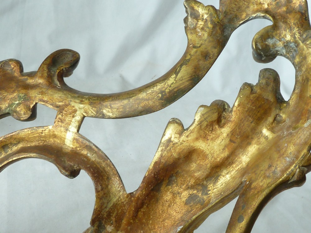 A pair of cast gilt brass French Rococo style fire dogs with elaborate acanthus leaf C-scroll design on small pedestal feet. View VI