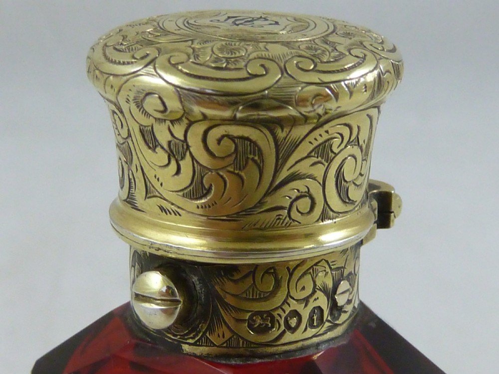 A faceted rectangular ruby red glass scent bottle featuring intricate scroll-engraved silver-gilt mounts at the cap and base. View VII