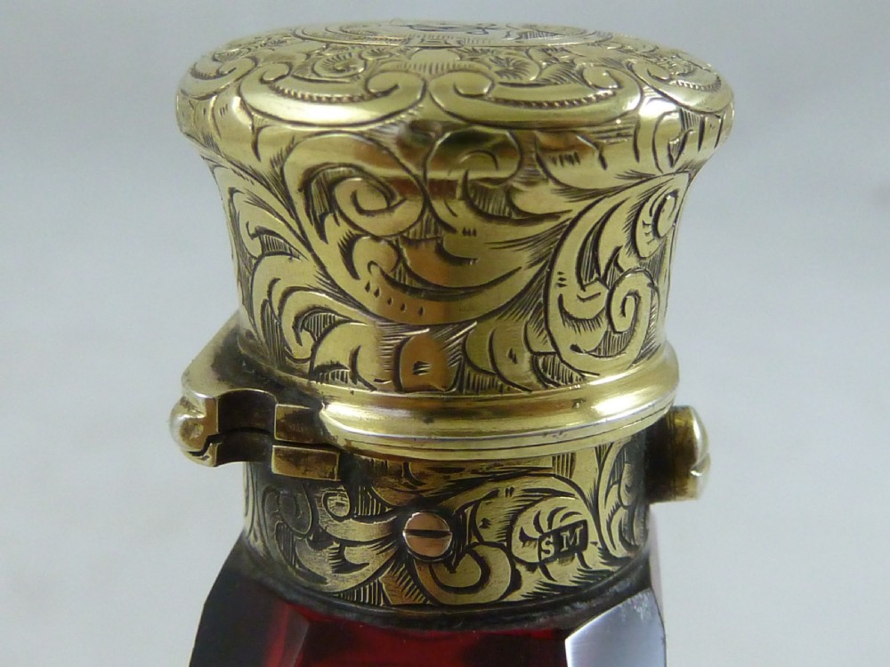 A faceted rectangular ruby red glass scent bottle featuring intricate scroll-engraved silver-gilt mounts at the cap and base. View VIII
