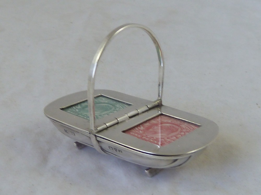 An Edwardian sterling silver double stamp case shaped like a garden trug with an overhead handle and two glazed stamp display compartments. View II