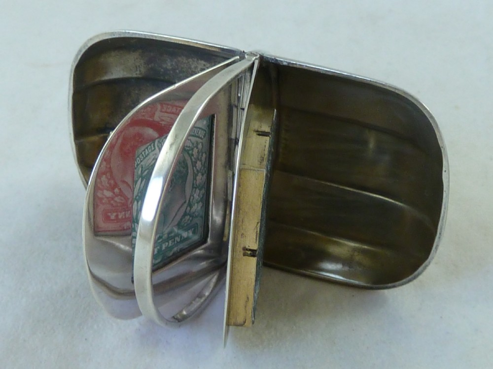 An Edwardian sterling silver double stamp case shaped like a garden trug with an overhead handle and two glazed stamp display compartments. View V