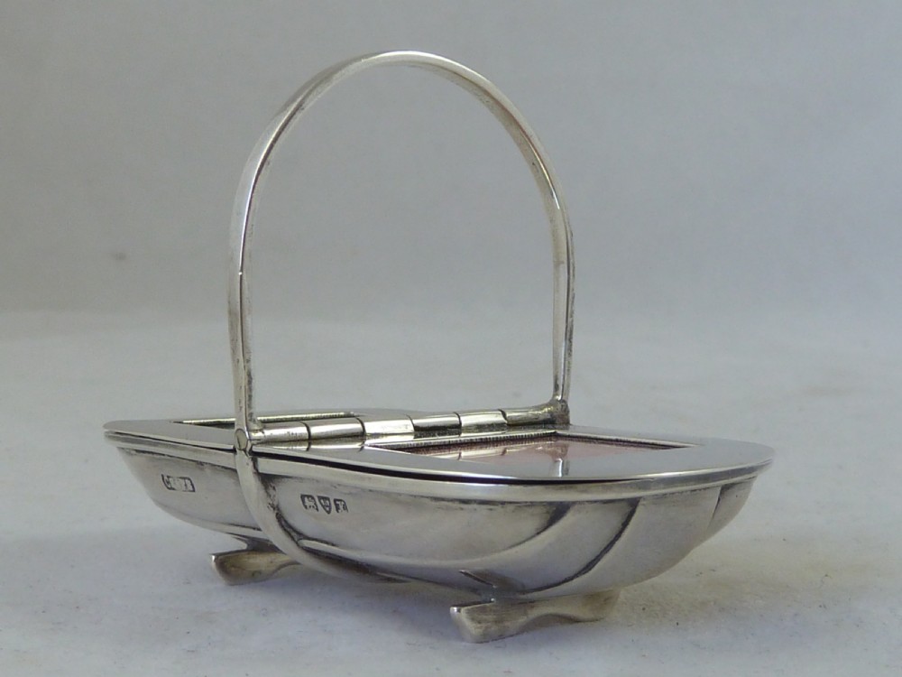 An Edwardian sterling silver double stamp case shaped like a garden trug with an overhead handle and two glazed stamp display compartments. View X