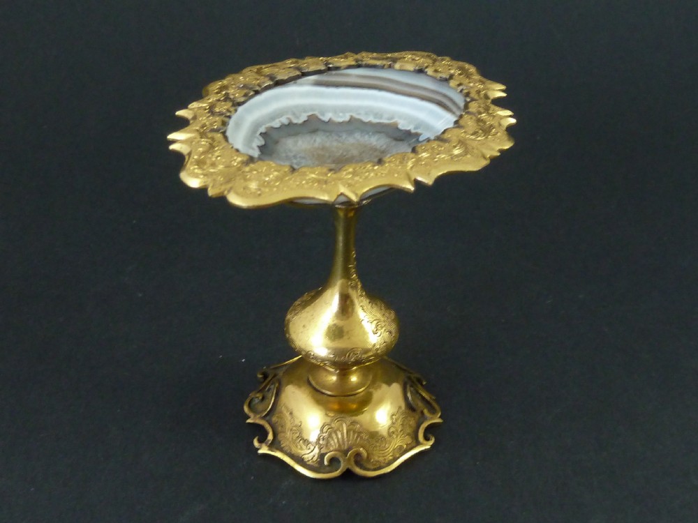 A miniature gilt brass tazza bowl featuring a central polished banded agate stone set within a chased Rococo scrollwork edge and pedestal foot. View IV
