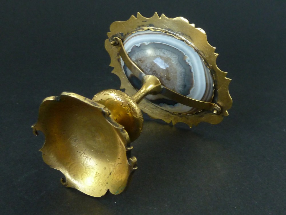 A miniature gilt brass tazza bowl featuring a central polished banded agate stone set within a chased Rococo scrollwork edge and pedestal foot. View VI