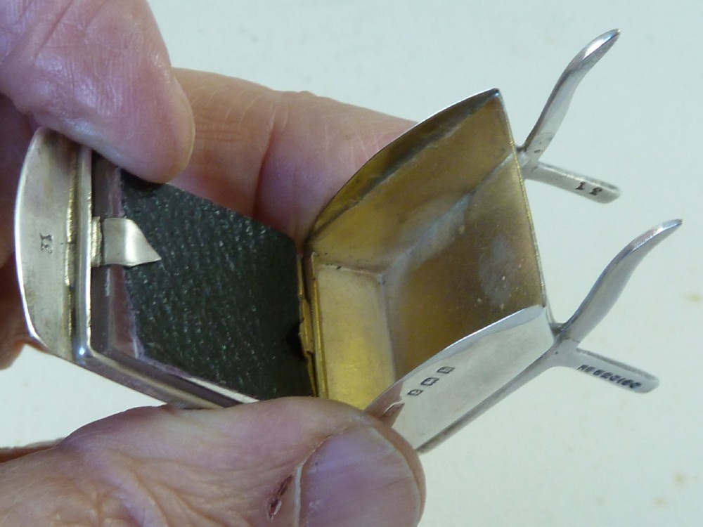 A miniature sterling silver stamp case shaped like a garden wheelbarrow with a clear glass window displaying a pink postage stamp. View IV