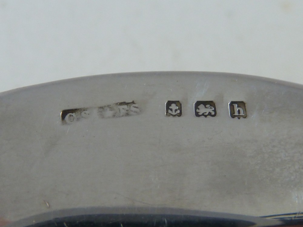 A miniature sterling silver stamp case shaped like a garden wheelbarrow with a clear glass window displaying a pink postage stamp. View V