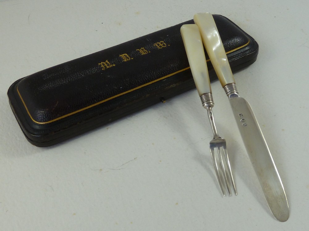 A boxed two-piece Georgian silver fruit knife and fork set with mother-of-pearl handles inside a blue velvet-lined case. View III