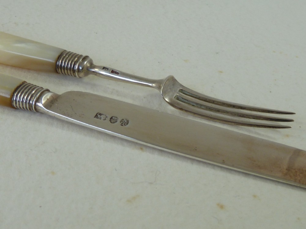 A boxed two-piece Georgian silver fruit knife and fork set with mother-of-pearl handles inside a blue velvet-lined case. View VI