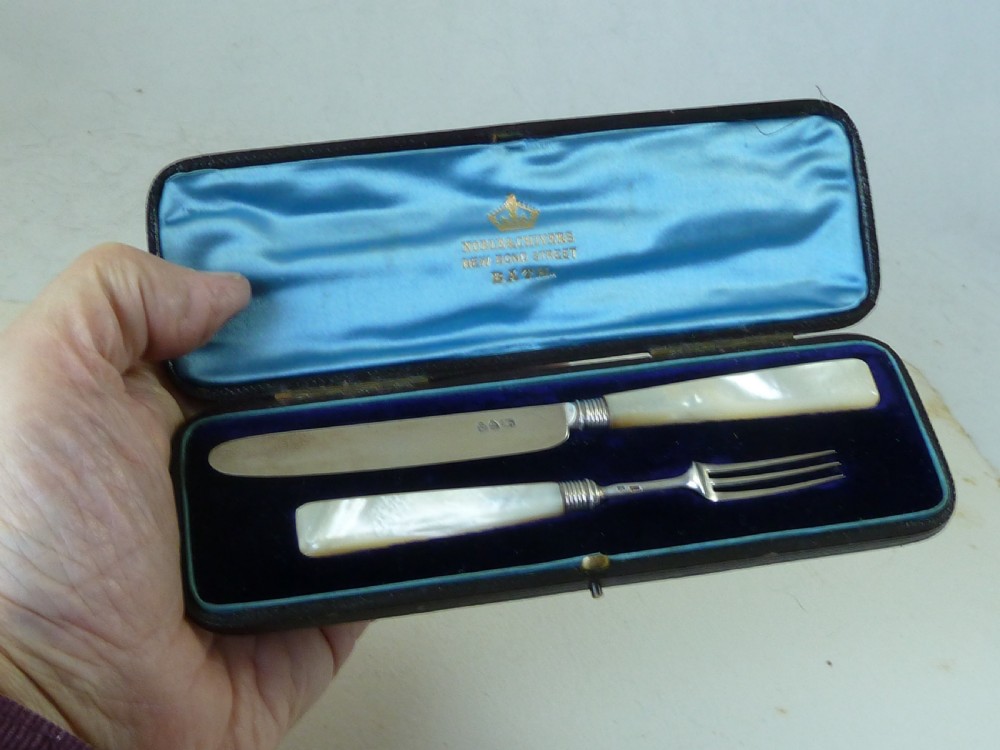 A boxed two-piece Georgian silver fruit knife and fork set with mother-of-pearl handles inside a blue velvet-lined case. View VII