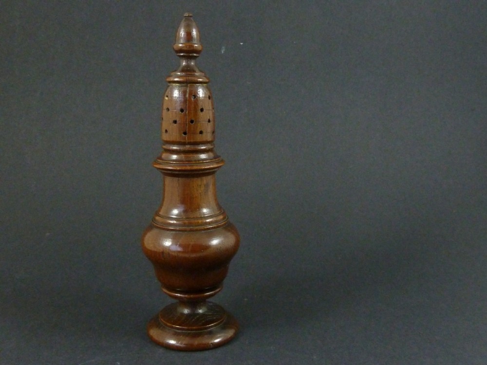 A turned dark wood sugar caster featuring a baluster form, pierced dome top with a finial, and a pedestal base.