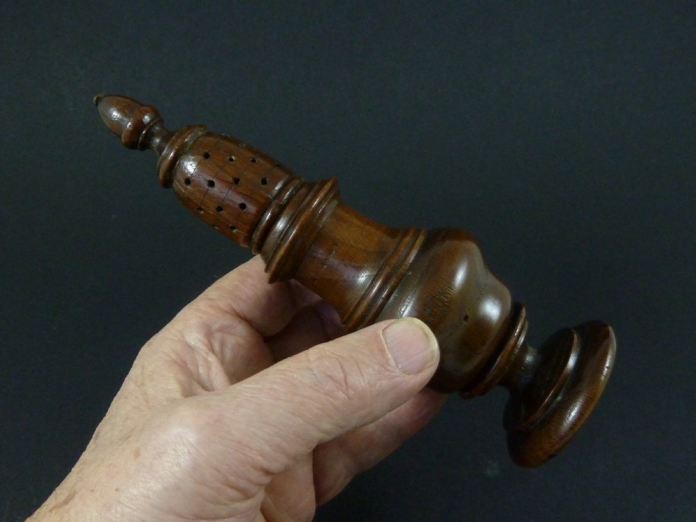 A turned dark wood sugar caster featuring a baluster form, pierced dome top with a finial, and a pedestal base. View VI