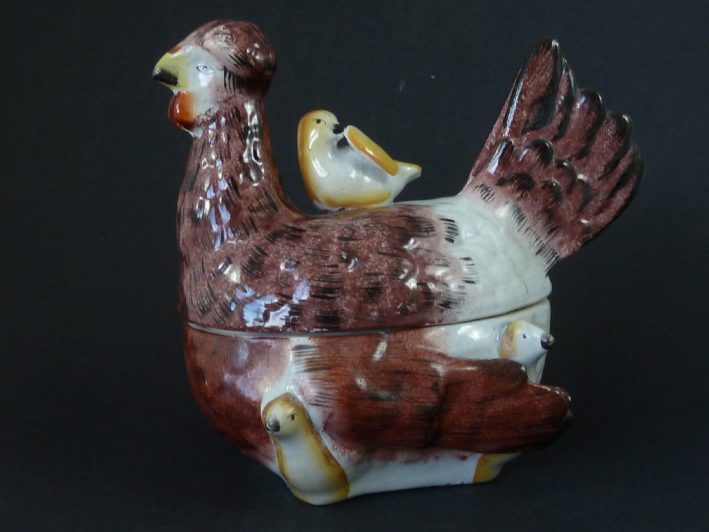 A Victorian glazed earthenware egg tureen shaped like a brown and white hen with small chicks resting along the lid and base.