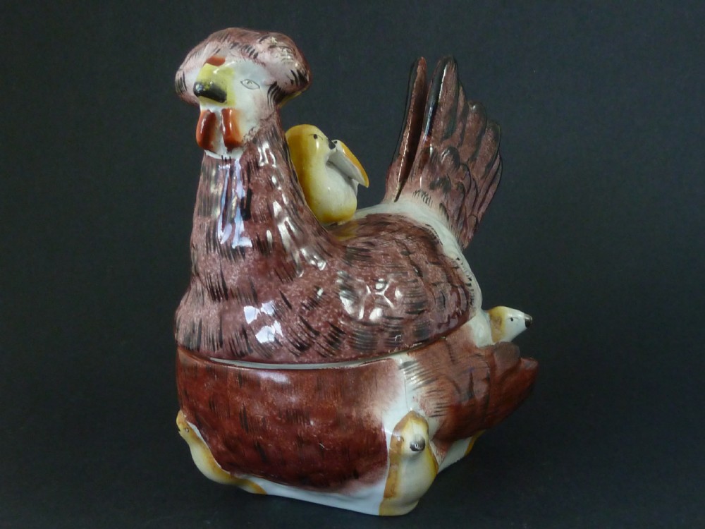 A Victorian glazed earthenware egg tureen shaped like a brown and white hen with small chicks resting along the lid and base. View II