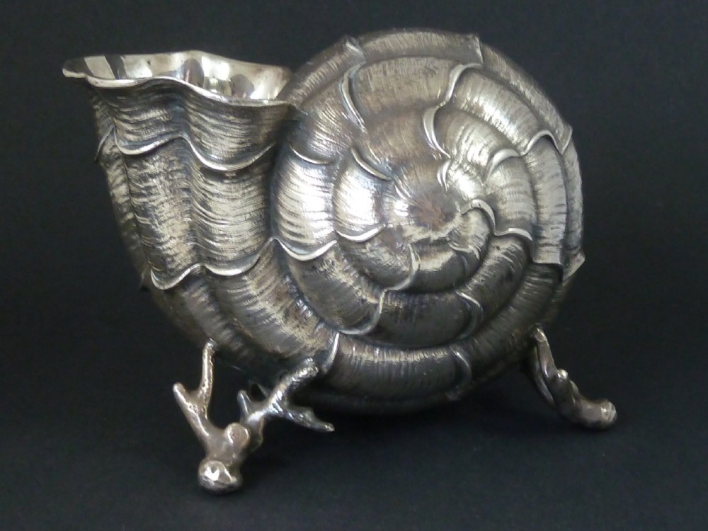 A Victorian electroplated nickel silver spoon warmer styled in the form of a nautilus shell supported by a cast coral branch base.