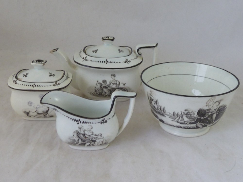 A Georgian era black transfer-printed miniature pearlware tea set featuring a teapot, sugar bowl, milk jug, bowls, cups, and saucers decorated with classical figural scenes. View IV