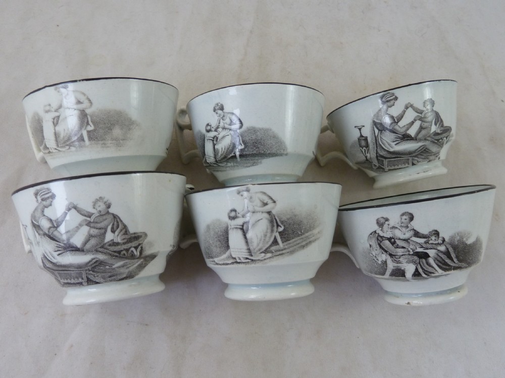 A Georgian era black transfer-printed miniature pearlware tea set featuring a teapot, sugar bowl, milk jug, bowls, cups, and saucers decorated with classical figural scenes. View XI