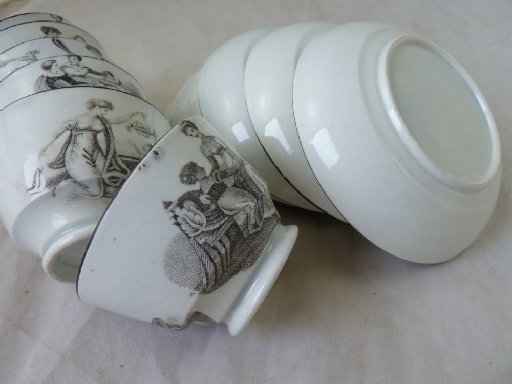 A Georgian era black transfer-printed miniature pearlware tea set featuring a teapot, sugar bowl, milk jug, bowls, cups, and saucers decorated with classical figural scenes. View XIII
