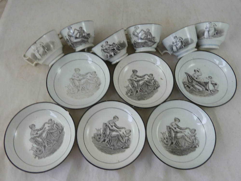 A Georgian era black transfer-printed miniature pearlware tea set featuring a teapot, sugar bowl, milk jug, bowls, cups, and saucers decorated with classical figural scenes. View XIV