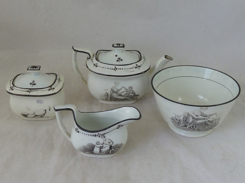 A Georgian era black transfer-printed miniature pearlware tea set featuring a teapot, sugar bowl, milk jug, bowls, cups, and saucers decorated with classical figural scenes. View XVII