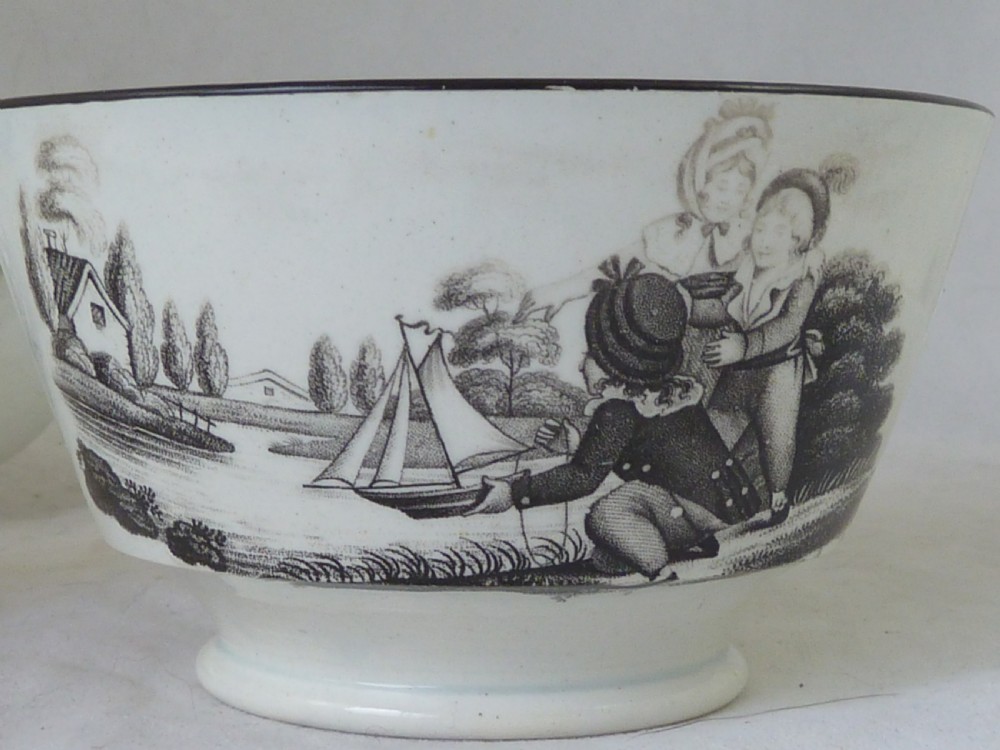 A Georgian era black transfer-printed miniature pearlware tea set featuring a teapot, sugar bowl, milk jug, bowls, cups, and saucers decorated with classical figural scenes. View XVIII