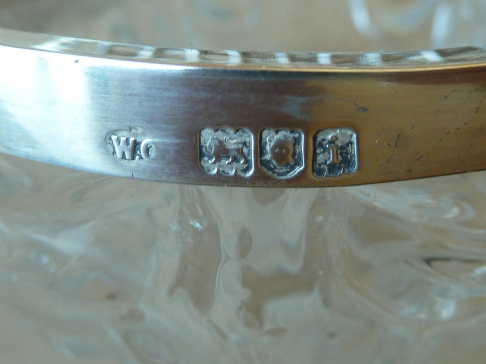 An oval clear cut glass bowl with a pierced silver floral lid and an overhead swing handle. View VIII