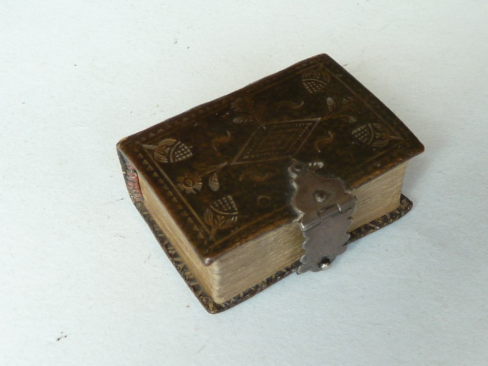 An 18th-century miniature leather-bound thumb bible featuring embossed acorn motifs and a metal clasp closure.