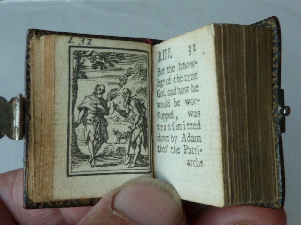 An 18th-century miniature leather-bound thumb bible featuring embossed acorn motifs and a metal clasp closure. View V