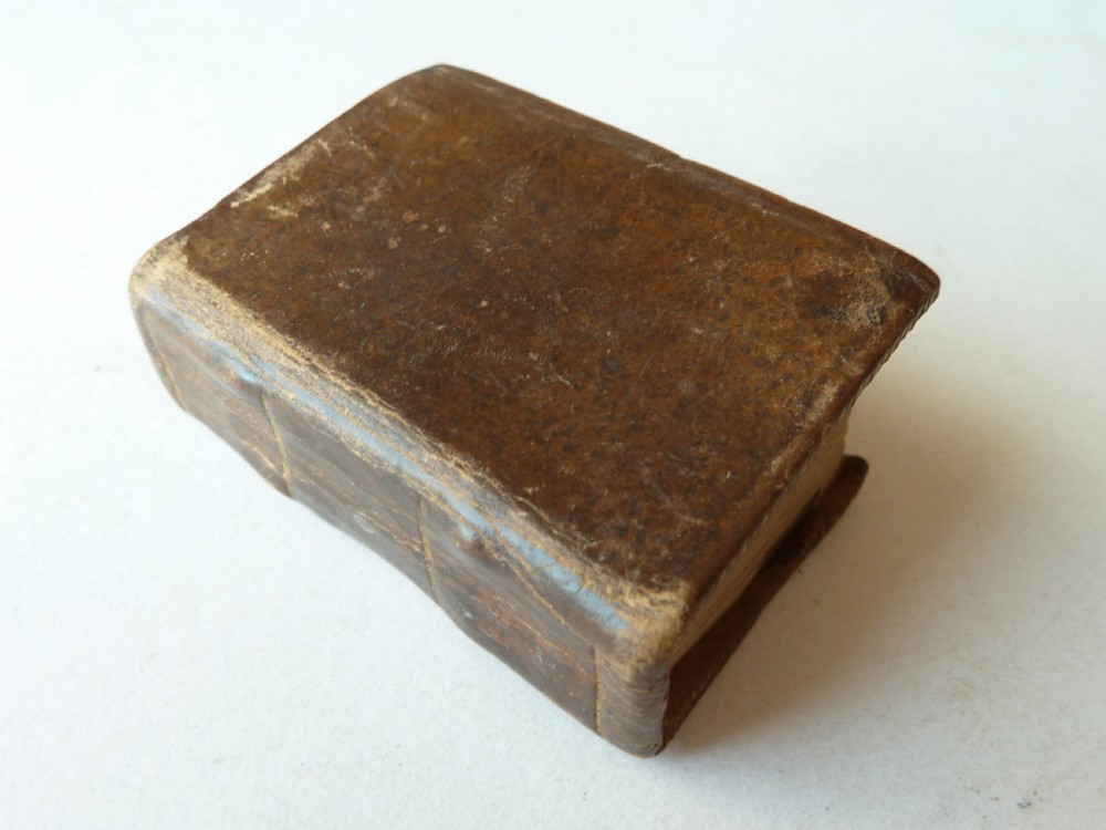 An eighteenth-century dark brown calfskin leather miniature bible with visible spine wear and raised bands.