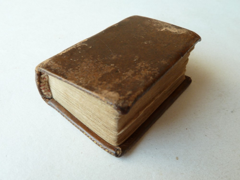 An eighteenth-century dark brown calfskin leather miniature bible with visible spine wear and raised bands. View II