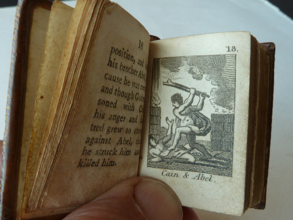 An eighteenth-century dark brown calfskin leather miniature bible with visible spine wear and raised bands. View V