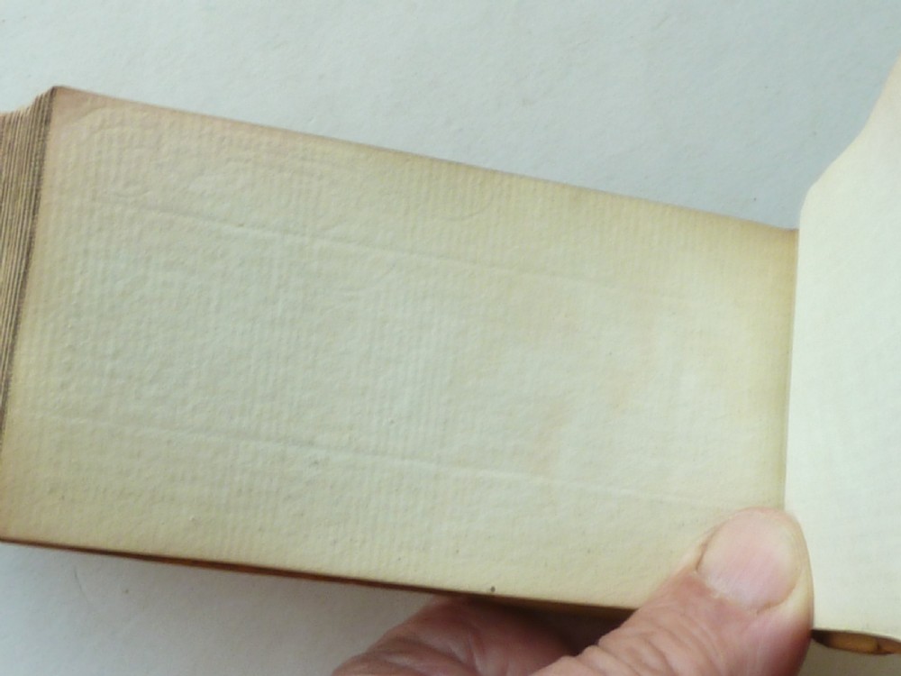 A small antique leatherbound book with a brown calfskin cover featuring gilt border tooling and aged paper edges. View X