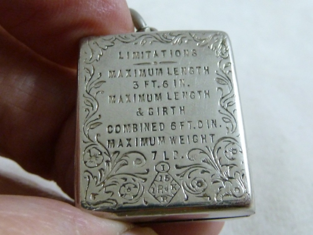 A rectangular Victorian silver-coloured metal stamp case fob featuring engraved scrollwork borders and etched text displaying inland parcel post rates. View II