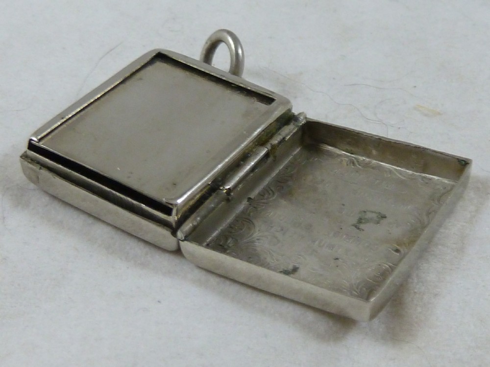 A rectangular Victorian silver-coloured metal stamp case fob featuring engraved scrollwork borders and etched text displaying inland parcel post rates. View V