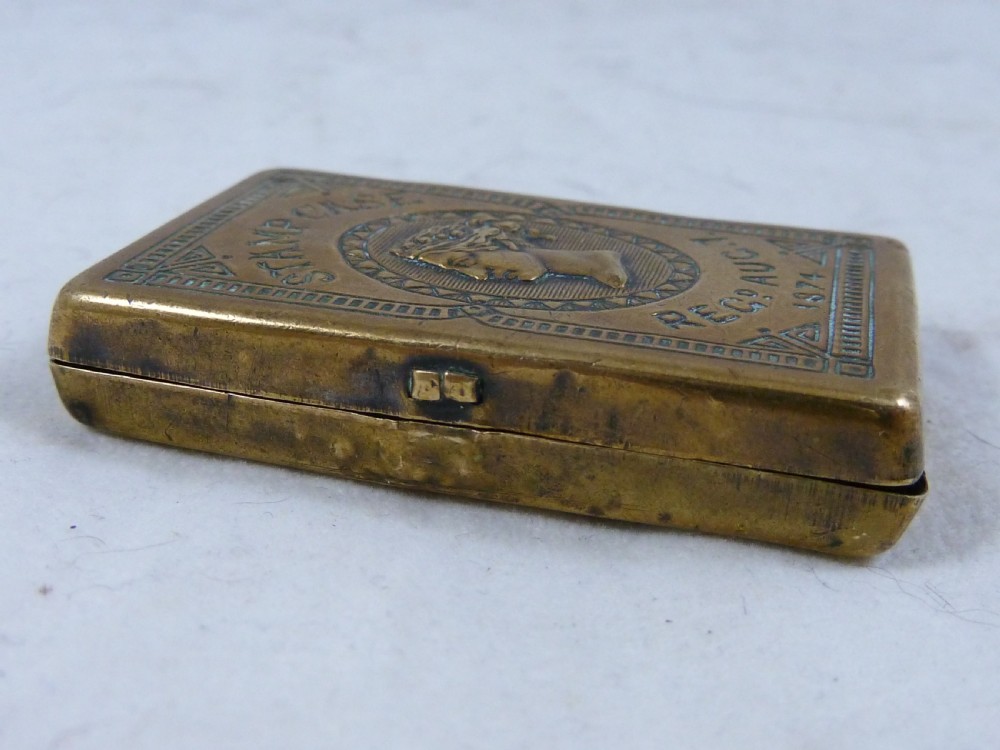 A small rectangular Victorian brass pocket stamp case embossed with a portrait of Queen Victoria and registration text dated 1874. View VII
