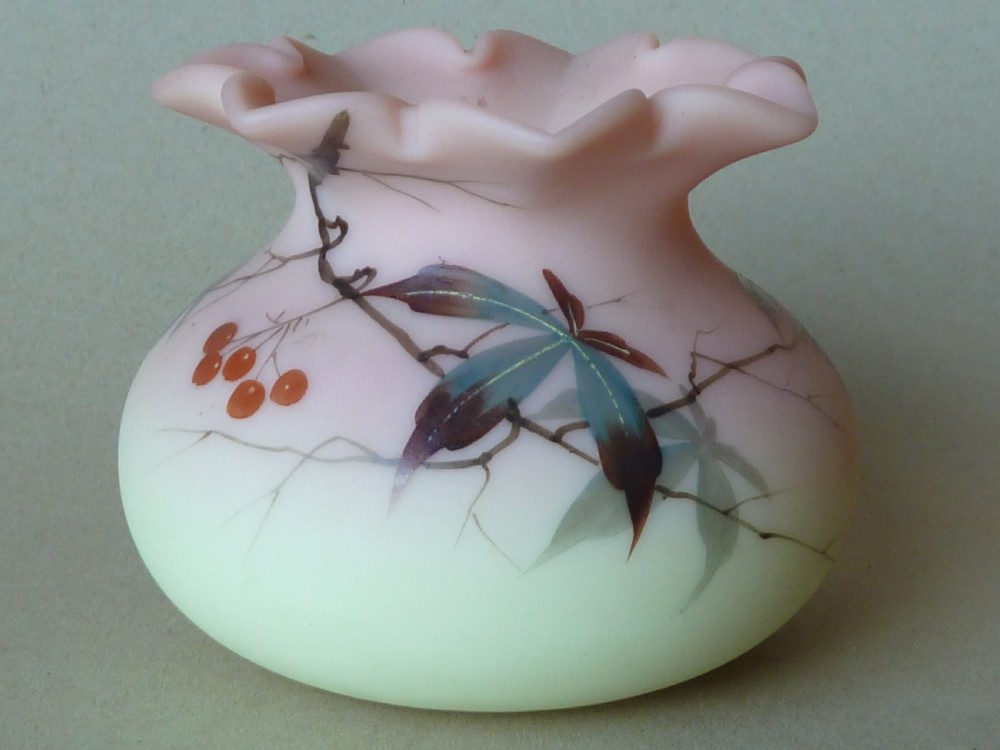A small Victorian Burmese satin glass vase with a crimped rim, shading from yellow at the base to pink at the top, decorated with hand-painted leaves and berries. View II