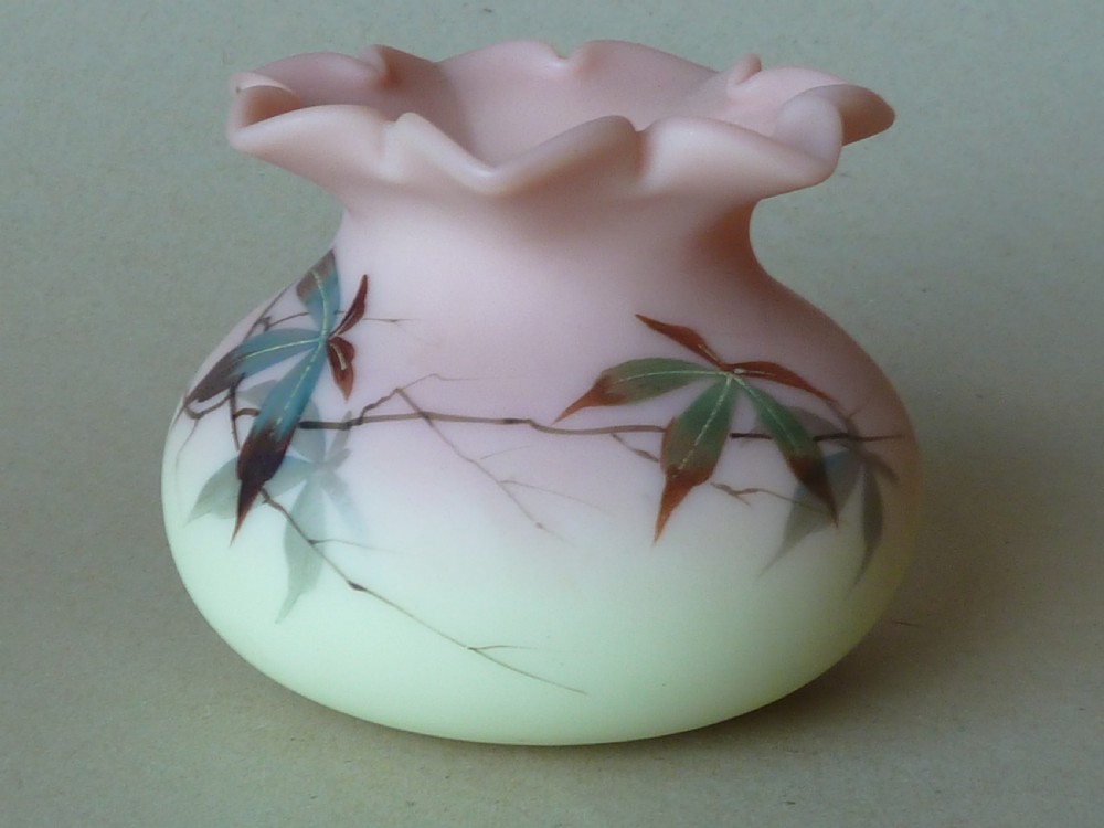 A small Victorian Burmese satin glass vase with a crimped rim, shading from yellow at the base to pink at the top, decorated with hand-painted leaves and berries. View III