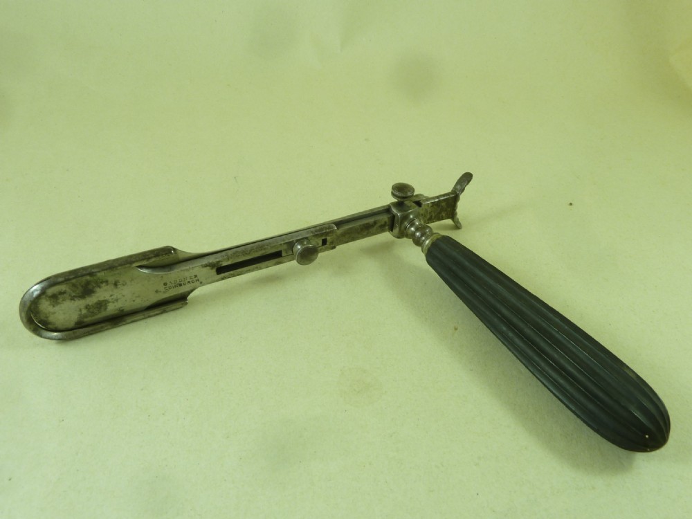 An antique metal tonsil guillotine featuring a long steel shaft with a sliding blade mechanism and a fluted black ebony handle.