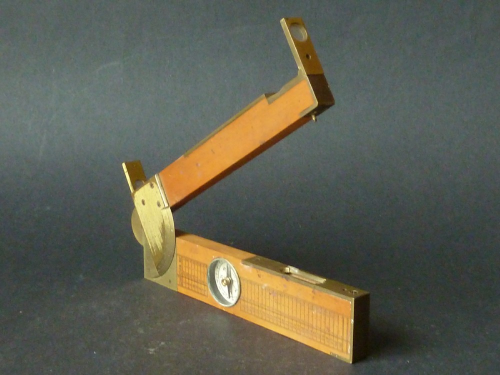 An antique boxwood and brass folding clinometer rule featuring an integrated magnetic compass, spirit level, folding sight vanes, and engraved measurement scales.