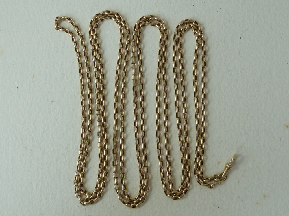 A long 14ct yellow gold Victorian guard chain featuring interlocking oval links and a dog clip clasp, laid flat against a neutral surface. View II