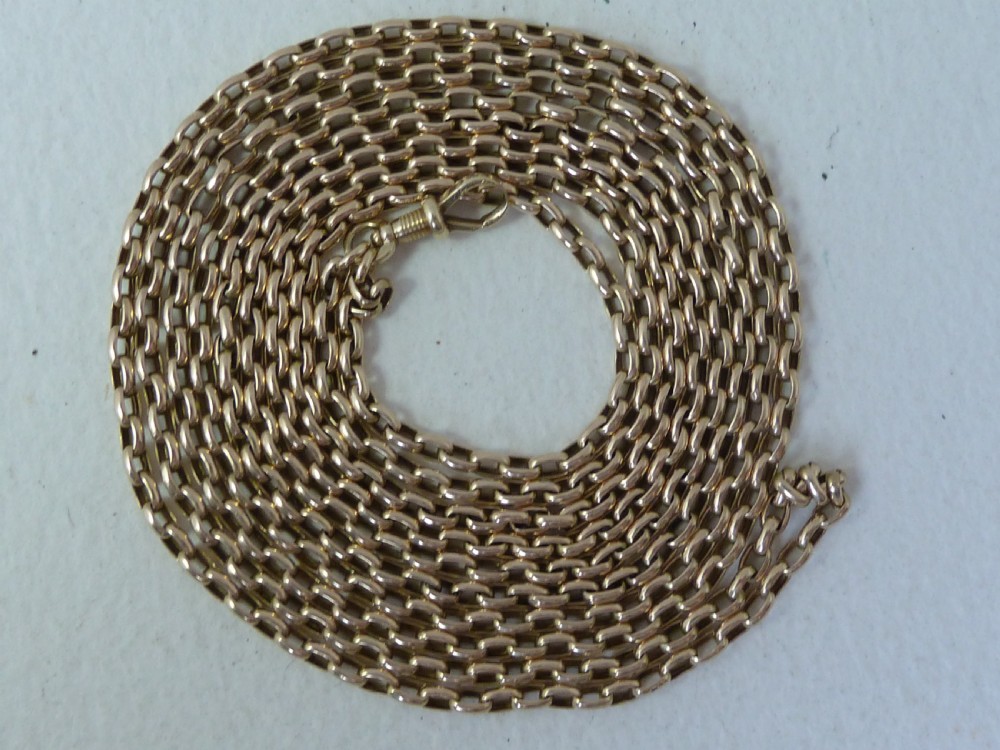 A long 14ct yellow gold Victorian guard chain featuring interlocking oval links and a dog clip clasp, laid flat against a neutral surface. View III