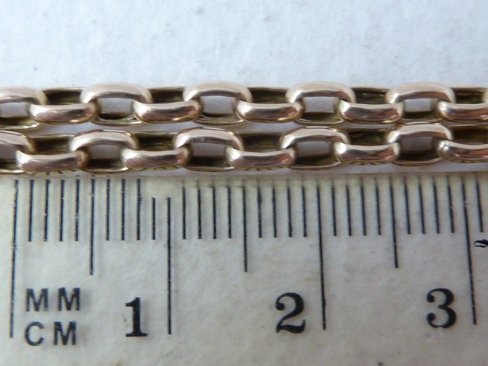 A long 14ct yellow gold Victorian guard chain featuring interlocking oval links and a dog clip clasp, laid flat against a neutral surface. View VI