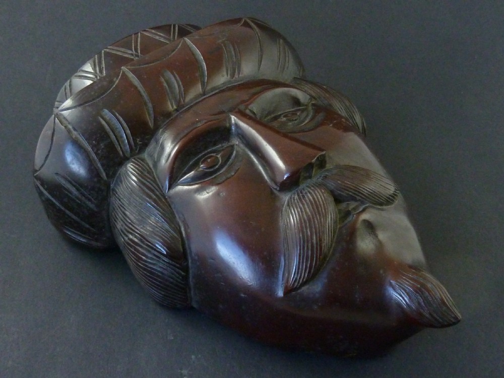 A polished dark hardwood wall mask depicting a turbaned man with a detailed moustache and beard. View III