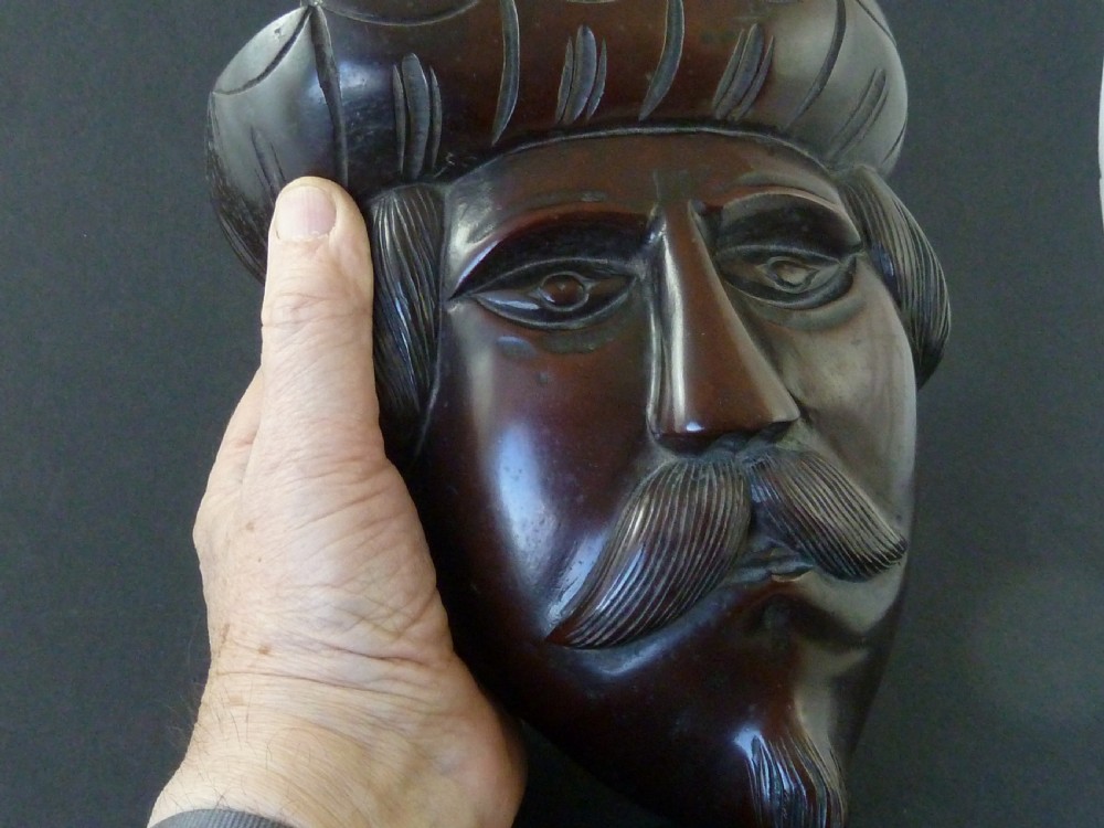 A polished dark hardwood wall mask depicting a turbaned man with a detailed moustache and beard. View VI