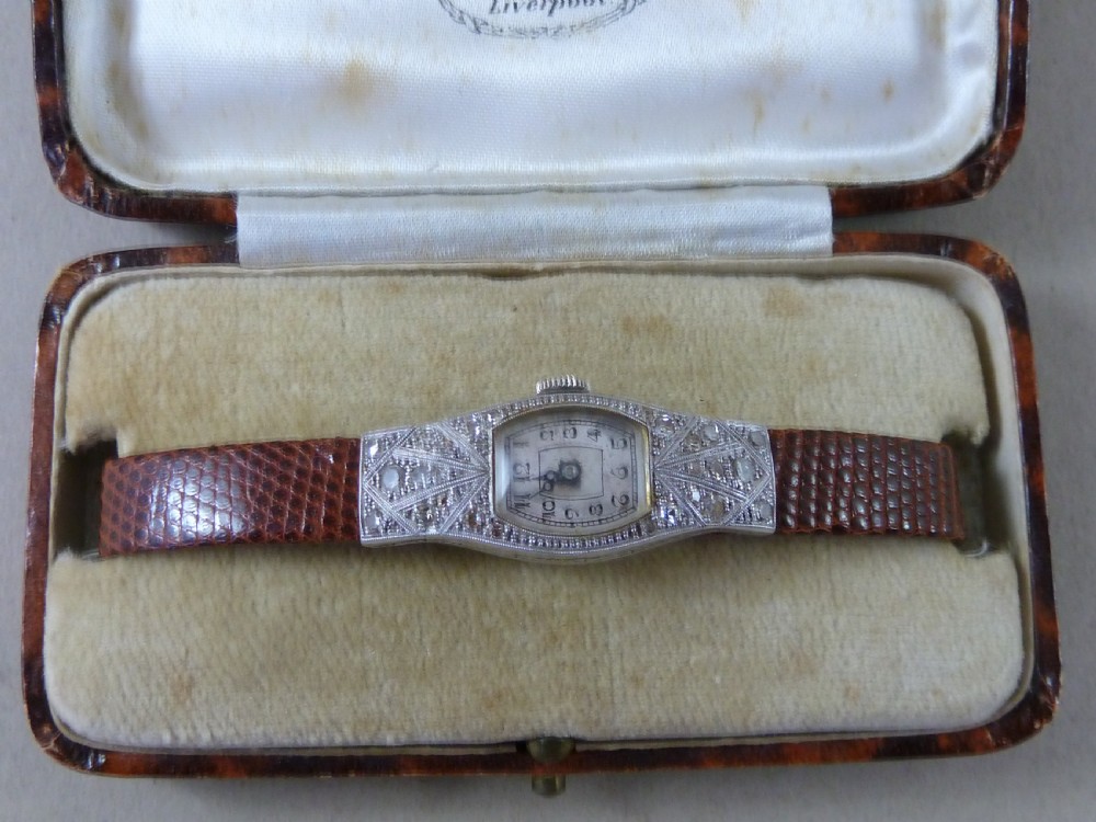 An Art Deco ladies cocktail watch with a white gold diamond-set geometric case, a cream dial, and a brown textured leather strap. View II