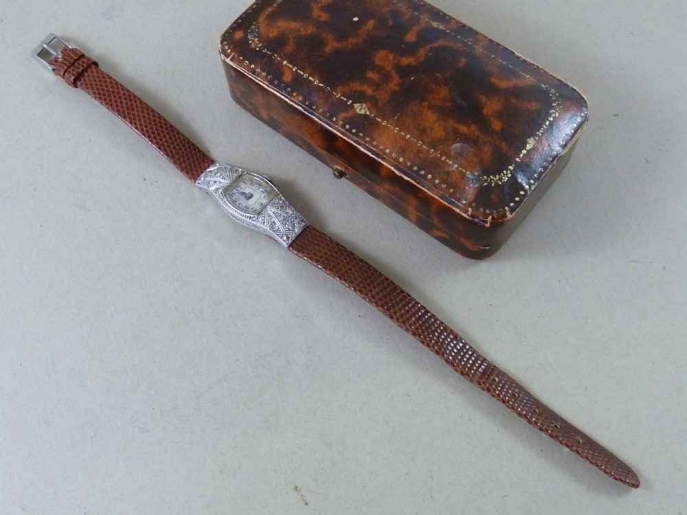 An Art Deco ladies cocktail watch with a white gold diamond-set geometric case, a cream dial, and a brown textured leather strap. View III