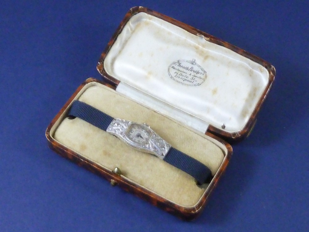 An Art Deco ladies cocktail watch with a white gold diamond-set geometric case, a cream dial, and a brown textured leather strap. View IV