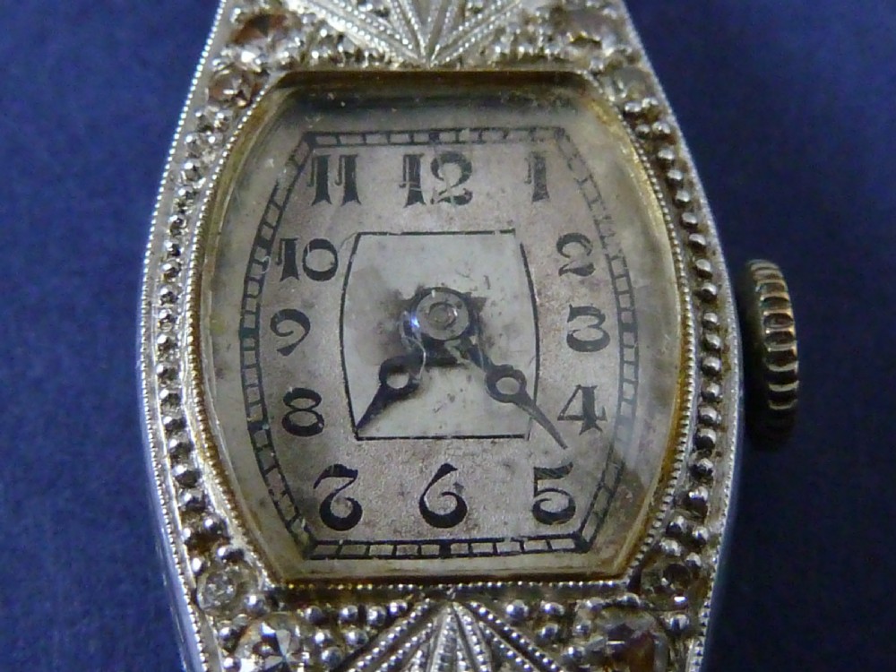 An Art Deco ladies cocktail watch with a white gold diamond-set geometric case, a cream dial, and a brown textured leather strap. View VI