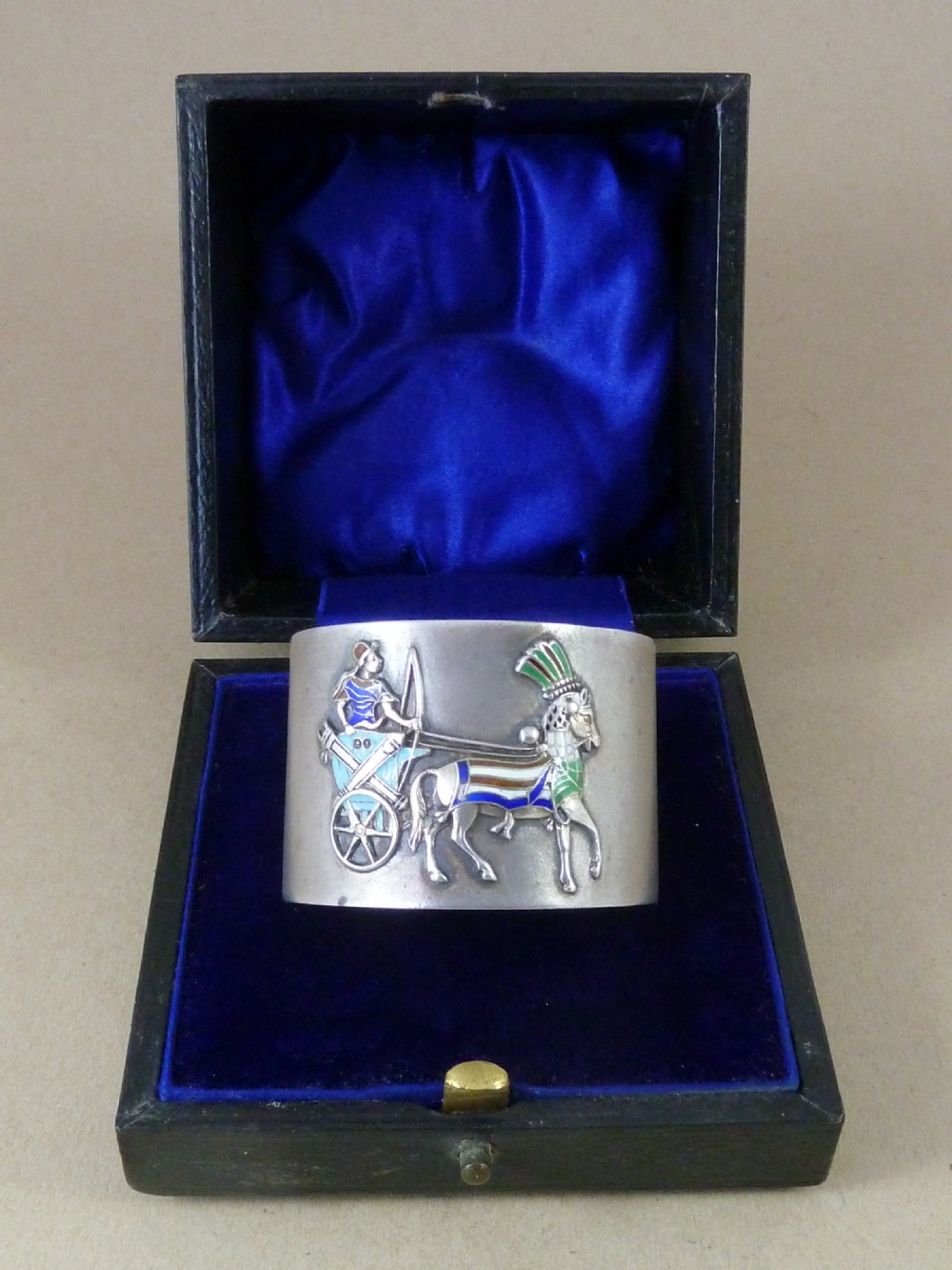 A curved 800 silver napkin ring featuring a detailed enamel relief depiction of a charioteer driving a horse in blue and green tones. View II